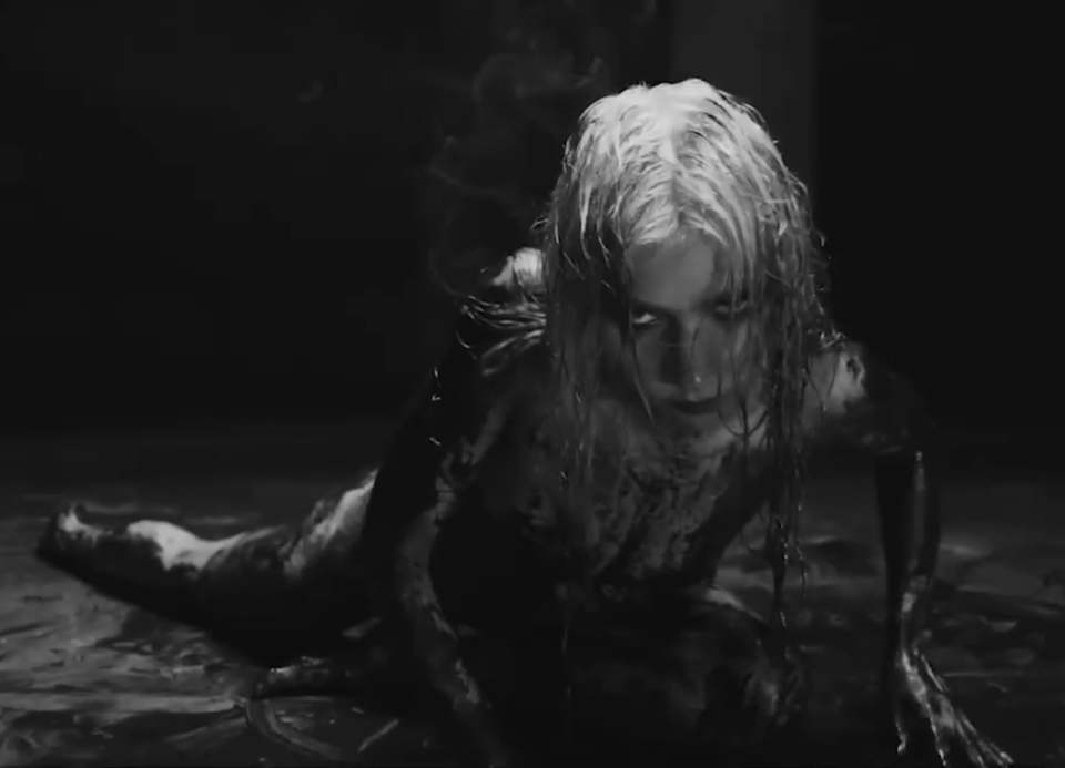 Photographie en noir et blanc d'une femme couverte de liquide noir.